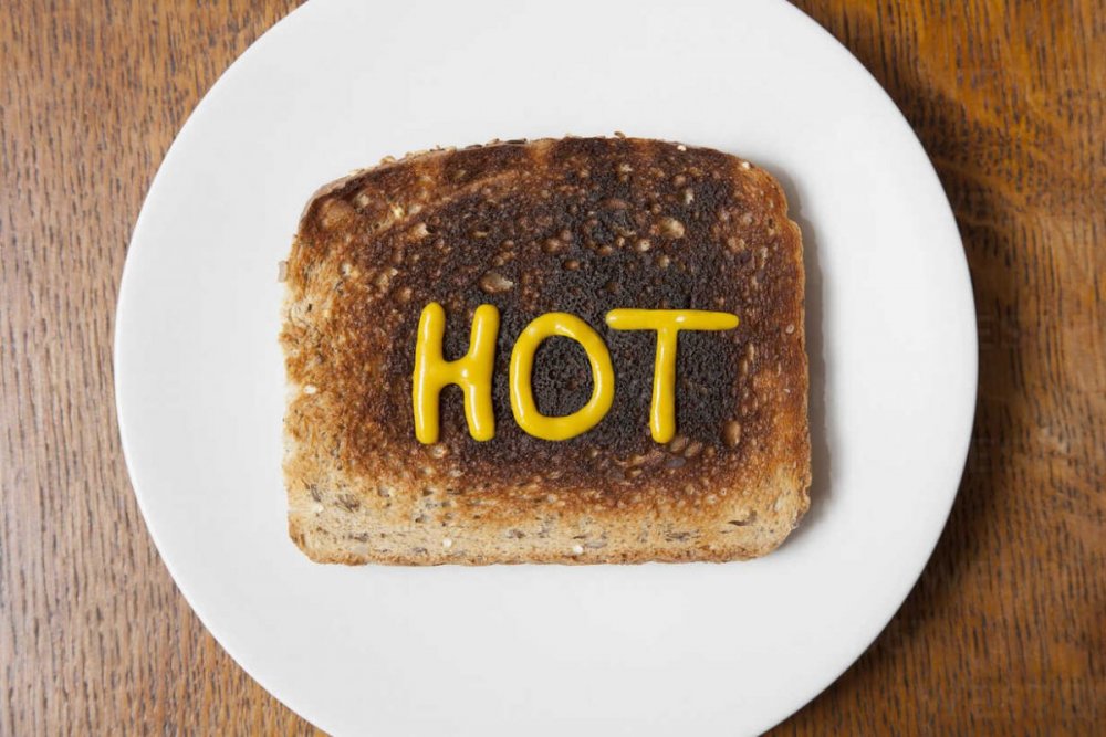 overhead-view-of-the-word-hot-written-in-mustard-on-burnt-toast-CUF19788.jpg